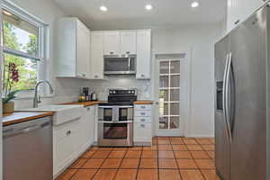 Kitchen featuring appliances with stainless steel finishes, a sink, backsplash, recessed lighting, and white cabinets