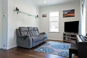 Living room with crown molding, dark wood-style floors, baseboards, and recessed lighting