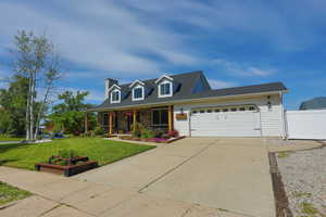 Cape cod-style house featuring an attached garage, covered porch, concrete driveway, and a chimney