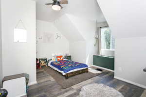 Bedroom featuring wood finished floors, a textured ceiling, vaulted ceiling, baseboards, and ceiling fan