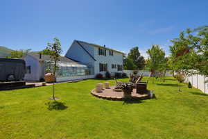 View of yard featuring a sunroom, a fire pit, and a patio