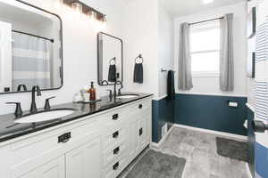 Full bath with ornamental molding, double vanity, and baseboards