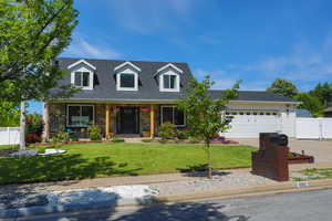 New england style home with a garage, concrete driveway, a porch, a shingled roof, and stone siding