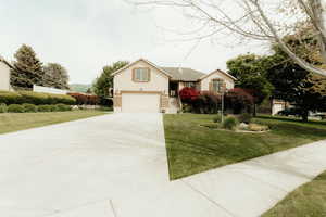 View of front facade with driveway, a garage, a front yard, and brick siding