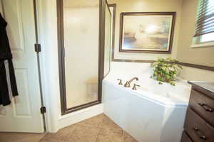 Full bath with a stall shower, tile patterned flooring, a bath, and vanity