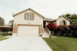 View of front facade featuring brick siding, driveway, a garage, and stucco siding