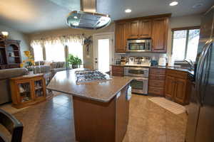 Kitchen with appliances with stainless steel finishes, a sink, brown cabinetry, open floor plan, and recessed lighting