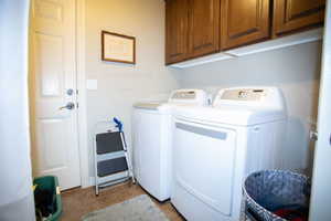 Laundry area featuring washer and clothes dryer, cabinet space, and tile patterned floors