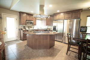 Kitchen with appliances with stainless steel finishes, island range hood, a kitchen island, recessed lighting, and plenty of natural light