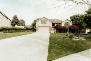 View of front of house with driveway, an attached garage, and a front lawn