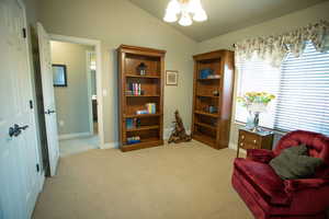Living area featuring a chandelier, vaulted ceiling, light colored carpet, and baseboards