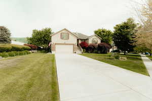 View of front facade featuring a garage, driveway, a front lawn, and brick siding