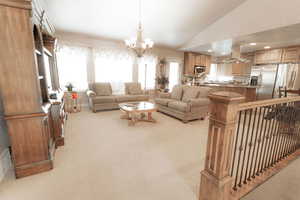Living room featuring light carpet, plenty of natural light, vaulted ceiling, a chandelier, and recessed lighting