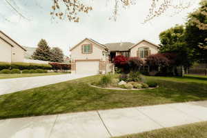 Traditional-style house featuring a garage, concrete driveway, a front lawn, and stucco siding