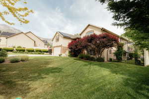 View of property hidden behind natural elements featuring an attached garage, solar panels, stucco siding, and concrete driveway