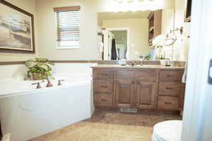 Bathroom with vanity, a garden tub, tile patterned floors, and toilet