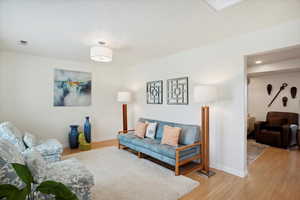 Living room with light wood-type flooring, baseboards, and recessed lighting