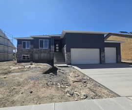 Prairie-style house featuring stone siding, a garage, and driveway