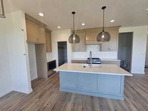 Kitchen with baseboards, light countertops, tasteful backsplash, wood finished floors, and a textured ceiling