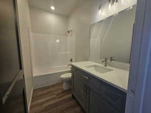 Bathroom featuring wood finished floors, vanity, toilet,  shower combination, and recessed lighting