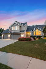 Traditional-style house with driveway, a front yard, stucco siding, an attached garage, and stone siding