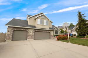 Traditional home with concrete driveway, stucco siding, a shingled roof, and brick siding