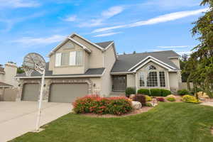 Traditional home featuring a front lawn, driveway, an attached garage, roof with shingles, and stucco siding