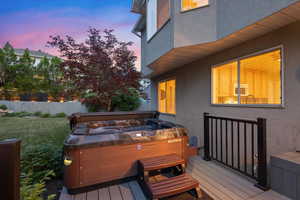 Deck at dusk featuring a hot tub