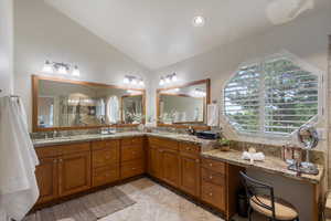 Bathroom with lofted ceiling, double vanity, tile patterned flooring, and a tile shower