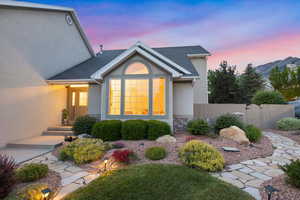 Back of property at dusk featuring stucco siding, a shingled roof, and a gate
