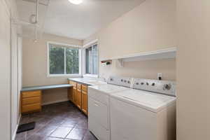 Washroom with cabinet space, washing machine and clothes dryer, an office area, and baseboards