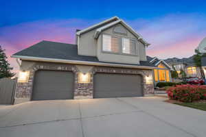 Traditional-style house featuring driveway, brick siding, stucco siding, an attached garage, and roof with shingles