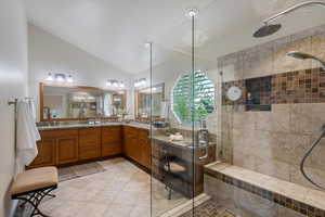 Full bathroom featuring a shower stall, vaulted ceiling, double vanity, and tile patterned flooring