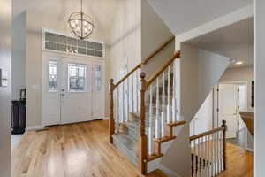 Entrance foyer with wood finished floors, a chandelier, stairway, a high ceiling, and baseboards