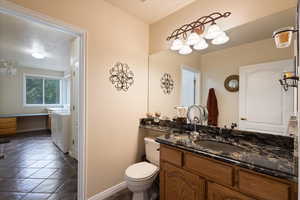 Bathroom featuring toilet, vanity, baseboards, and washer / clothes dryer