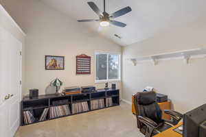 Home office featuring a ceiling fan, carpet floors, and lofted ceiling