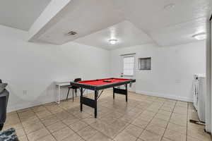 Playroom featuring baseboards, pool table, washer and dryer, light tile patterned floors, and a textured ceiling
