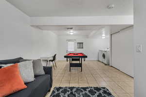 A versatile living space with a washer and a dryer; light tile patterned floors; walkout