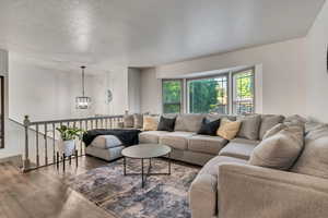 Living room featuring bay windows, contemporary laminate flooring, a chandelier, and baseboards
