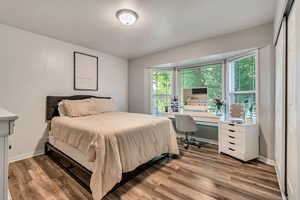 Bedroom with bay windows, a beauty table, contemporary laminate flooring, and baseboards