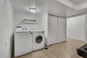 Laundry area featuring washer and dryer, a textured ceiling, and light tile patterned floors