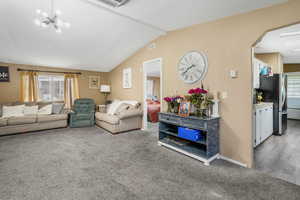 Living room featuring carpet floors, healthy amount of natural light, arched walkways, and a chandelier