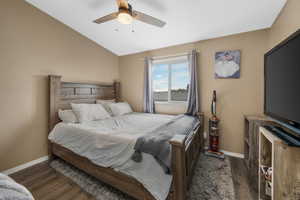 Bedroom featuring vaulted ceiling, wood finished floors, baseboards, and ceiling fan