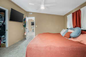 Bedroom with light carpet, a closet, and a ceiling fan