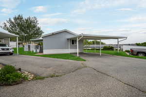 View of home's exterior featuring a lawn, asphalt driveway, and an attached carport