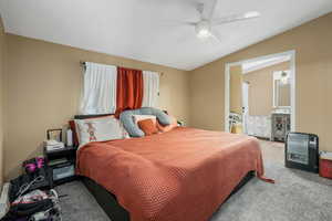Bedroom featuring vaulted ceiling, ceiling fan, and carpet