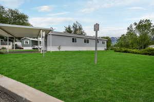View of side of property featuring a carport, a lawn, and a mountain view