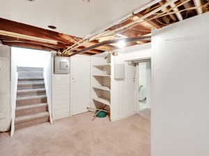 Basement featuring stairway, light carpet, and electric panel