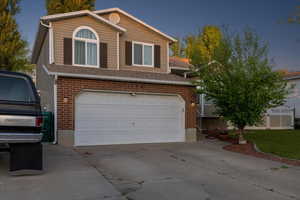 Tri-level home featuring brick siding, a garage, and concrete driveway