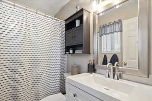 Bathroom with vanity, toilet, and a shower with shower curtain